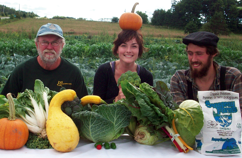 Reg Phelan, Carina Phillips and Byron Petrie showcase a table filled with vegetables grown on their farm, Seaspray Organics