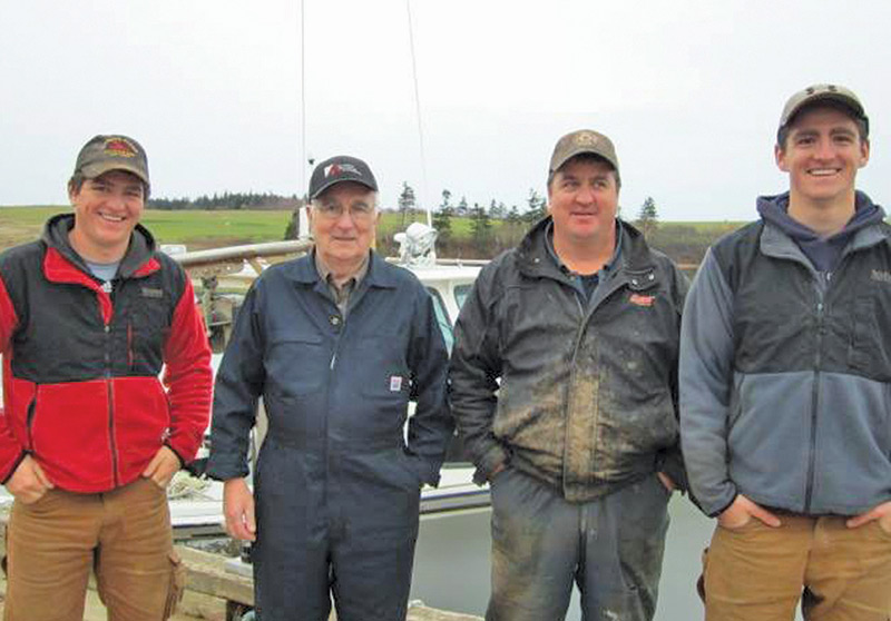 Four lobster fishermen representing three generations of the Blacketts pose in front of a fishing boat.