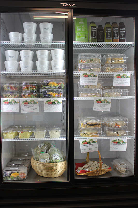 Cooler with glass doors stocked with prepared soups, salads and other dishes.