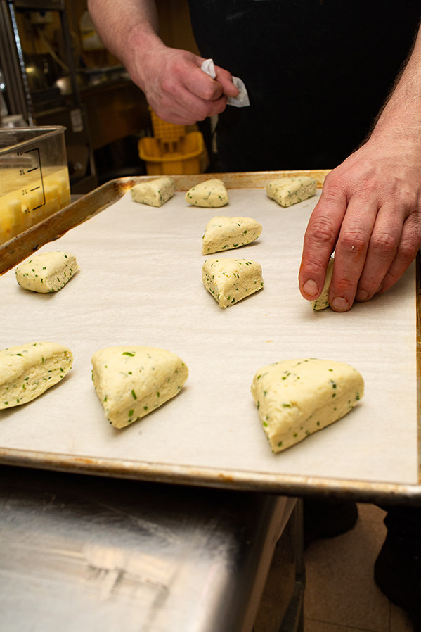 Wedges of dough are placed on the parchment-lined cookie sheet to go into the oven.