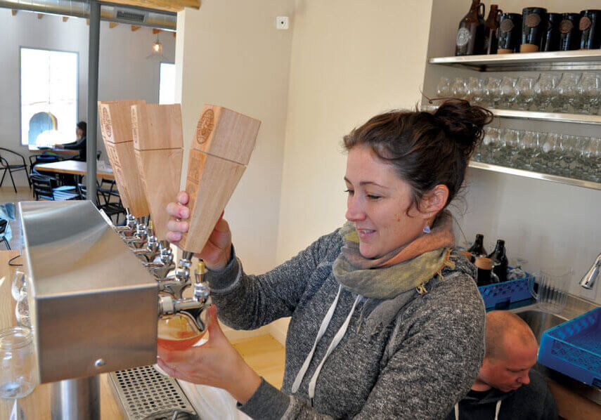 Ashley Condon, co-owner of Copper Bottom Brewing pours a pint at the brewery's newly opened taproom//Photo Credit: Rod Weatherbie