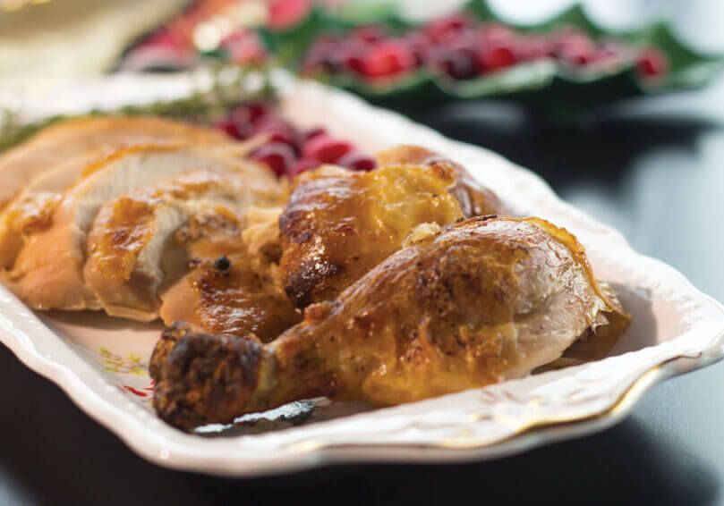 brined, roasted chicken sliced on a plate with cranberries