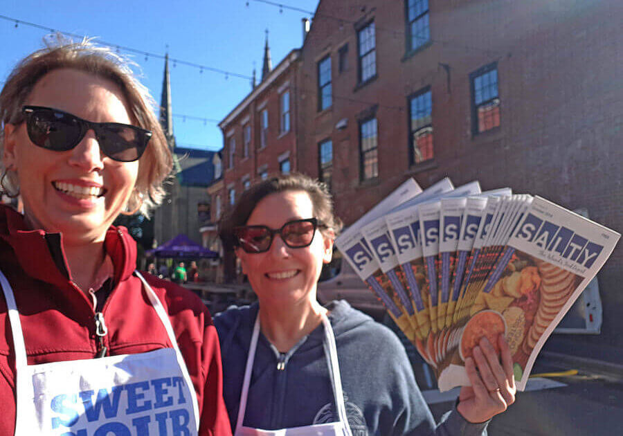 Cheryl Young and Laura Weatherbie hold up printed copies of Salty at Farm Day in the City