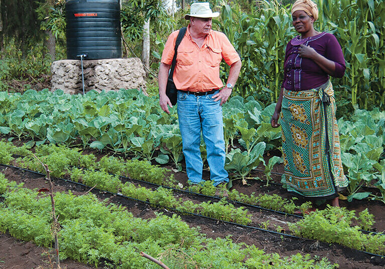 Farmers Helping Farmers volunteer helping a member of the Upendo Women's Self Help Group in the garden